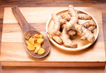 Turmeric root in wooden plate, Turmeric Thai herb on a wooden table background.