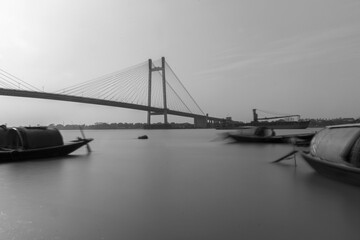 Anchored floating boats on river Hoogly with Vidyasagar Setu or 2nd Hoogly bridge in background.