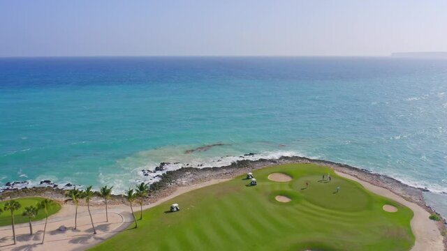People play golf seaside at Corales Golf Course, Punta Cana Resort in Dominican Republic. Aerial forward ascending