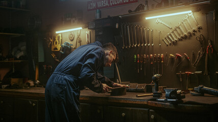 Young blacksmith checking his tools and supplies to get to work in his workshop, back view