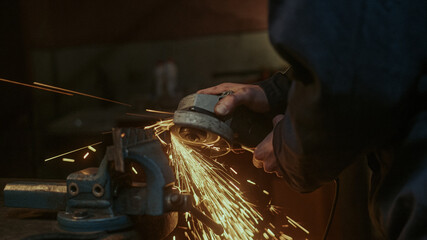 Close-up use iron or metal cutting machine and he metal grinding on steel spare part in workshop 