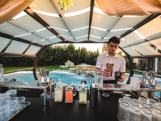 bartender mixing a cocktail outdoors near a pool in a resort