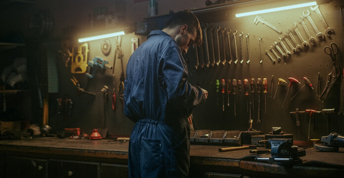 Young blacksmith man working standing at the workbench at his own workshop