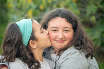 Two young girls embracing and kissing outdoor.