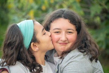 Fototapeta premium Two young girls embracing and kissing outdoor.