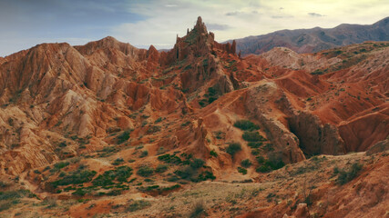 A magnificent aerial flight on a throne over a rocky red-orange canyon with green plants and rocks...