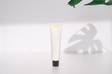 A white tube-type cosmetics container with a black lid.