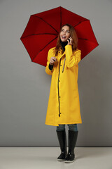 Young girl in yellow raincoat with red umbrella
