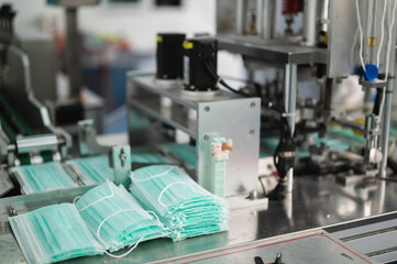 Both male and female Asian scientists are outfitted with protective gear. Examining the factory's machinery and materials used in the mask-making process. Covid 19 is a piece of preventive equipment.