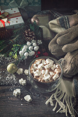 Winter concept. Hot chocolate cacao drink with marshmallows and Christmas present on a wooden table.