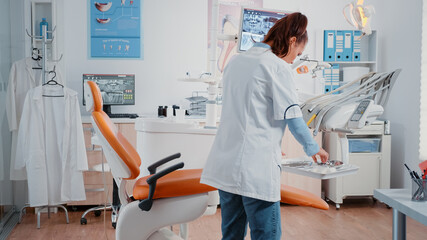 Dentist working with stomatology equipment for dental checkup in cabinet. Woman using tools and chair for oral care and dentistry, preparing for teeth examination in dentist office