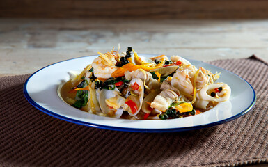 Stir-Fried Seafood  Thai food in white dish on apron and old wooden table