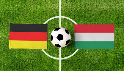 Top view soccer ball with Germany vs. Hungary flags match on green football field.