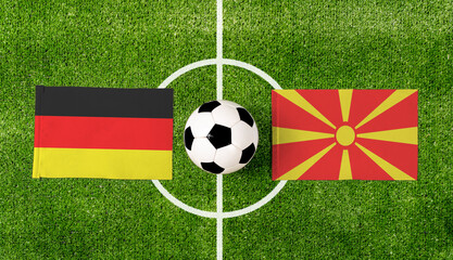 Top view soccer ball with Germany vs. Macedonia flags match on green football field.