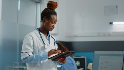 Medic looking at tablet screen for healthcare system in cabinet. Doctor with white coat using...
