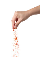 Hand sprinkling cayenne pepper on white background