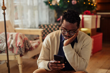 Bored man using cellphone at home