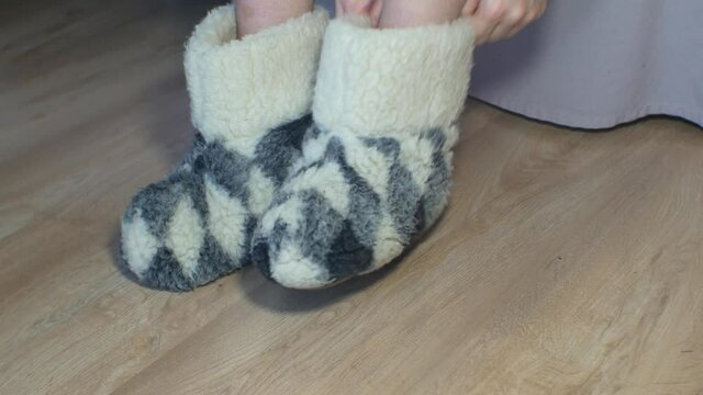Woman is wearing Home soft warm slippers. Warm home footwear, fluffy shoes. Cold winter weather.