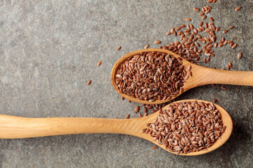 Wooden spoons with flaxseed on a stone background.