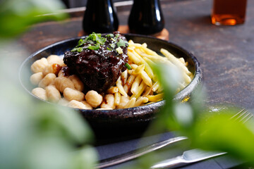 Roasted meat in bbq sauce with fries, and gnocchi.
A tasty dish.Culinary photography. Suggestion to serve the dish.