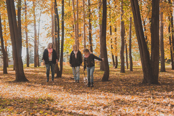 Grandmother and mother with granddaughter walks together in autumn park and having fun. Generation, leisure and family concept.