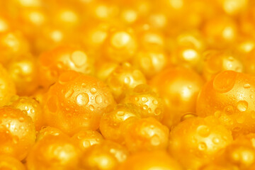 Beautiful background with pearl gold pearls, top view. Abstract texture for festive backgrounds. Shiny yellow surface of Christmas decorations. Gems close-up. Golden bright background.