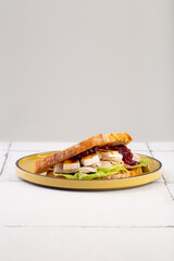 sandwich with cheese Bri chicken salad and jam on yellow plate