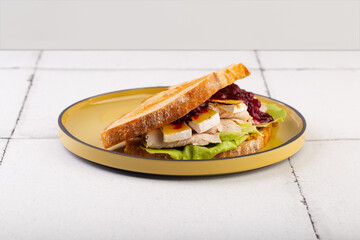 sandwich with cheese Bri chicken salad and jam on yellow plate