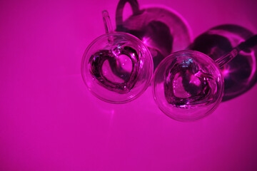 Image for valentine's day. Two glass mugs in the shape of hearts in bright light.