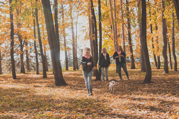 Fototapeta premium Grandmother and mother with granddaughter walks together in autumn park and having fun. Generation, leisure and family concept.