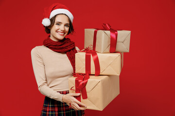 Young excited fun woman 20s wear Santa Claus Christmas red hat hold red present box with gift ribbon bow scream isolated on plain background studio portrait. Happy New Year 2022 celebration concept.