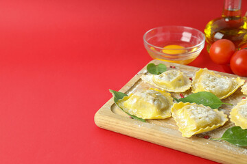 Concept of cooking ravioli on red background