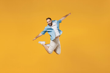 Fototapeta na wymiar Full body young smiling happy man 20s wear blue shirt white t-shirt jump high with outstretched hands like flying scream isolated on plain yellow background studio portrait. People lifestyle concept.