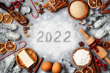 Bakery background with ingredients for cooking decorated with fir tree and new year 2022. Flour,...