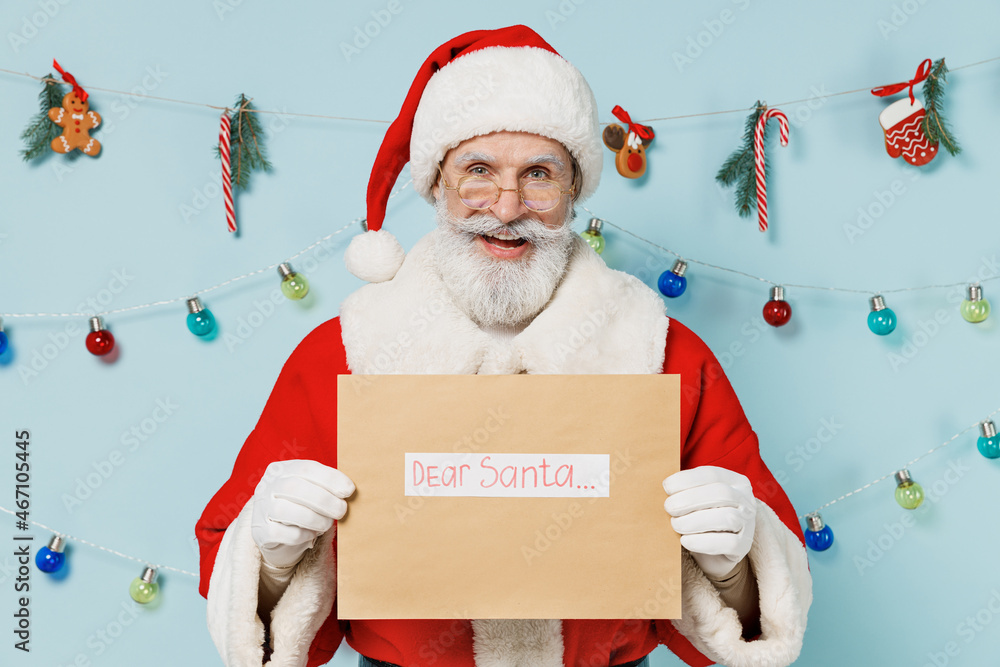 Wall mural Old smiling Santa Claus man wears Christmas hat red suit hold letter with dear santa title text isolated on plain blue background studio Happy New Year 2022 celebration merry ho x-mas holiday concept