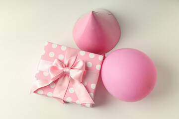Gift box, party hat and balloon on white background