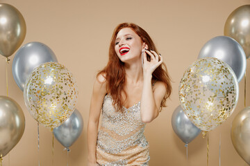 Young fun sexy stunning redhead woman 20s wearing evening dress near balloons showing earrings...