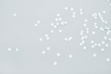 Silver stars confetti on gray background. Christmas or winter festive background