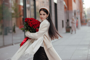 Happy woman holding bouquet of roses flowers in a city