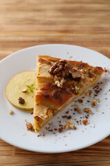 Piece of apple pie on plate on wooden background