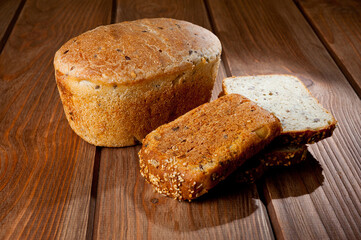 A loaf of delicious white bread made from natural products, on hops with flax saturation, without baker's yeast, on a wooden table surface.