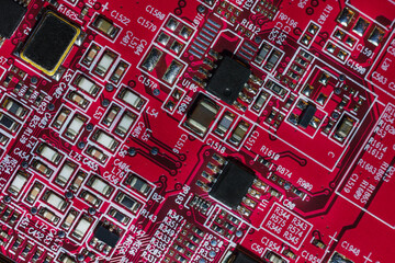Macro close-up shot of a microchip, cpu processor on a red high tech electronic printed circuit board (PCB), computer motherboard with components inside an electronic device, part of a graphics