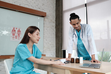 Healthcare team partners. Two uniformed young Asian ethnicity doctors are co-workers discussing...