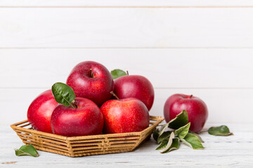 Ripe garden apple fruits with leaves in basket on wooden table. Top view flat lay with copy space