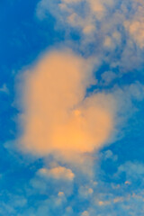 Abstract heart shape warm color cloud on blue sky in sunset time background.