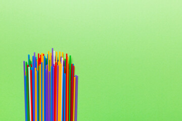 Heap of colorful plastic drinking straws on Colored background, flat lay. Copy Space for text