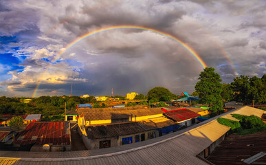 rainbow on cloudy sky over small town background.