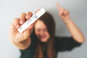 Negative rapid antigen COVID-19 test in hand of unrecognizable blurred person. Happy woman shows her test result. Travel during the coronavirus pandemic, avoid quarantine, new normal concept.