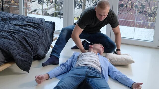 A man provides first aid to a friend with an epileptic seizure