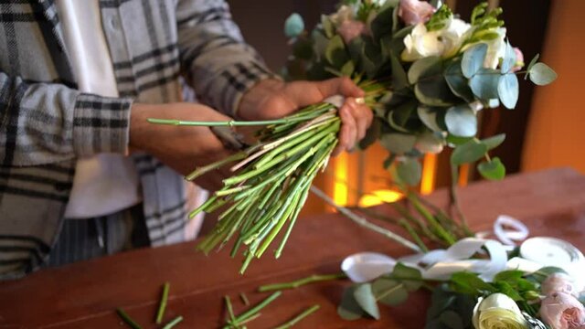 Man florist makes bouquet of flowers. Professional worker creating beautiful wedding bouquet.
